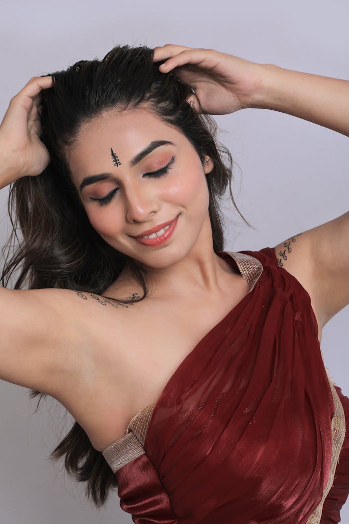 Smiling woman in red sari with henna, embracing Indian culture and tradition.